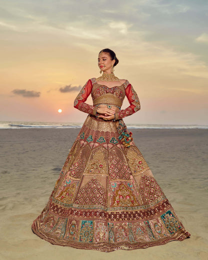 Woman in a traditional embroidered outfit standing on a beach at sunset.