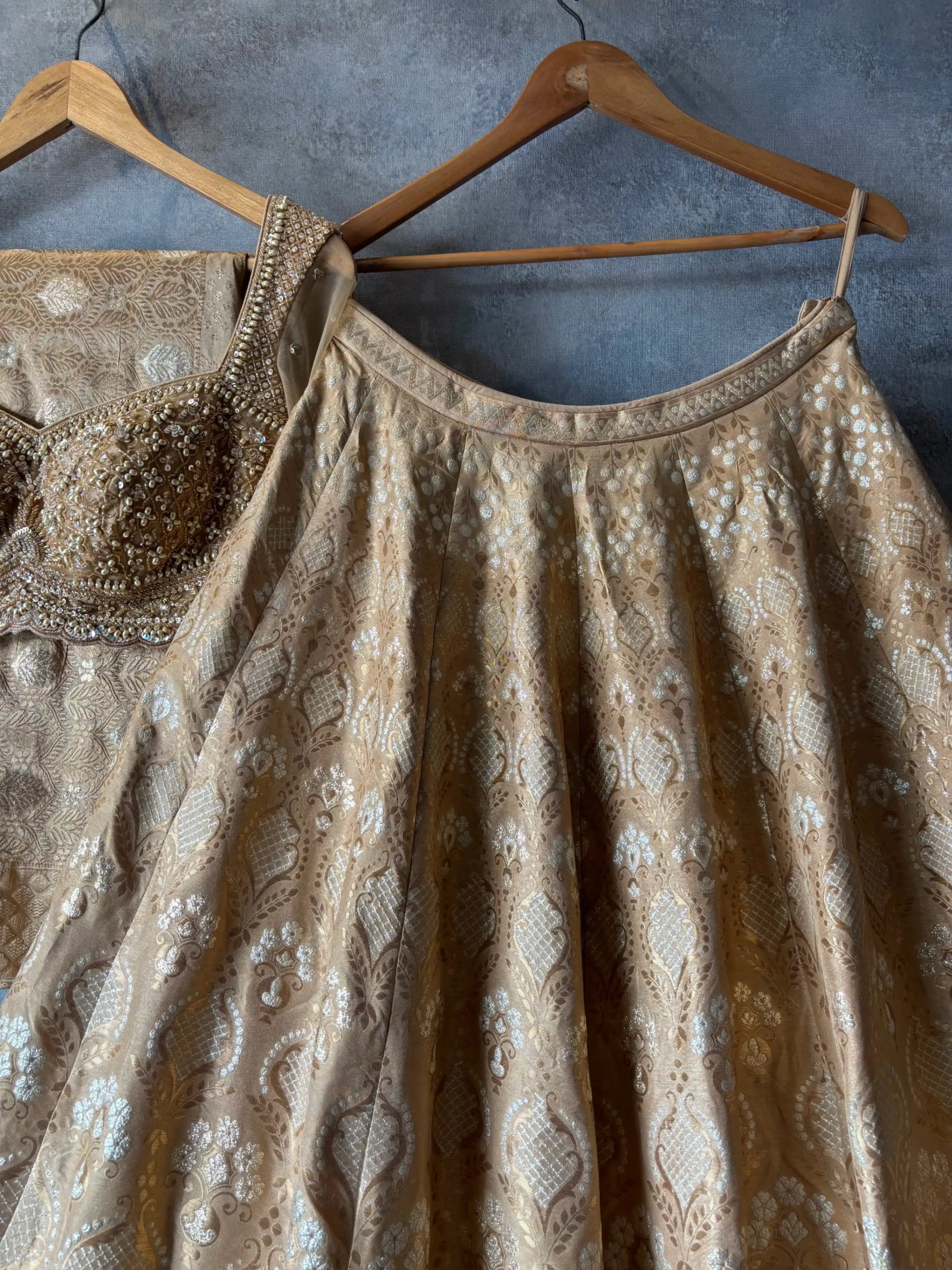 Brown embroidered dress on a hanger against a gray wall