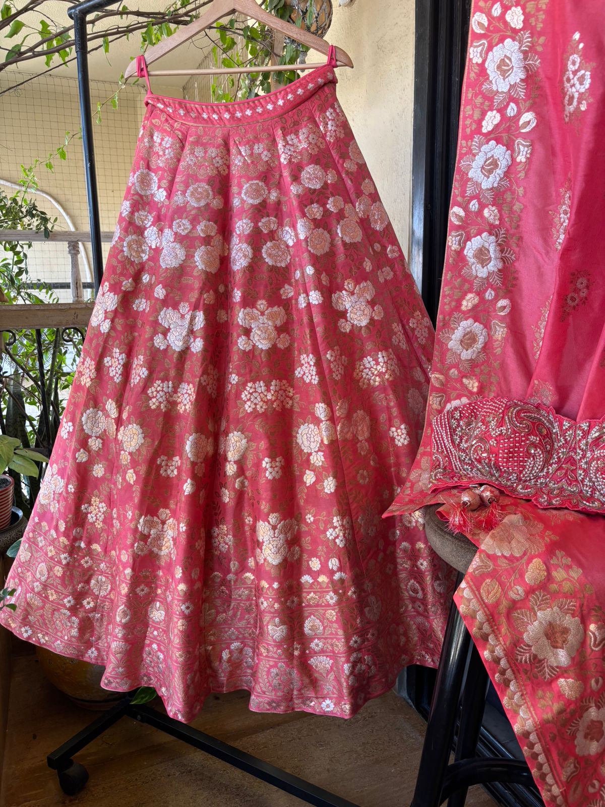 Pink floral skirt and matching blouse on a hanger with a blurred background