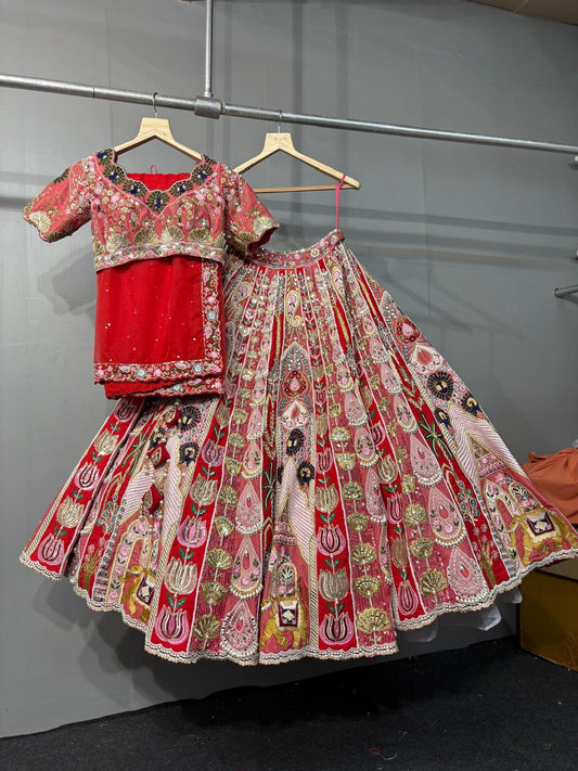 Traditional outfit with a floral blouse and red lehenga on hangers against a gray wall.