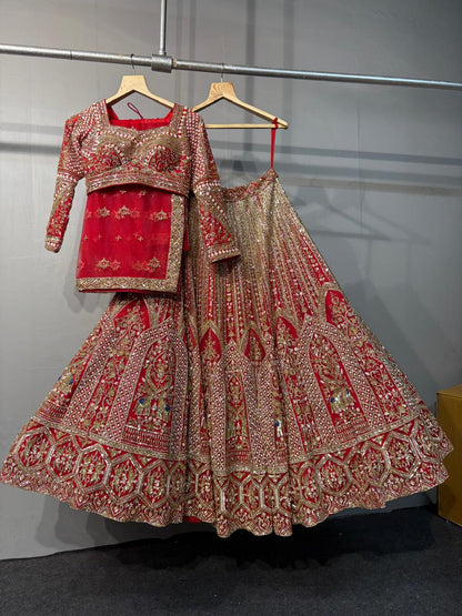 Traditional red and gold embroidered lehenga on a hanger against a gray background
