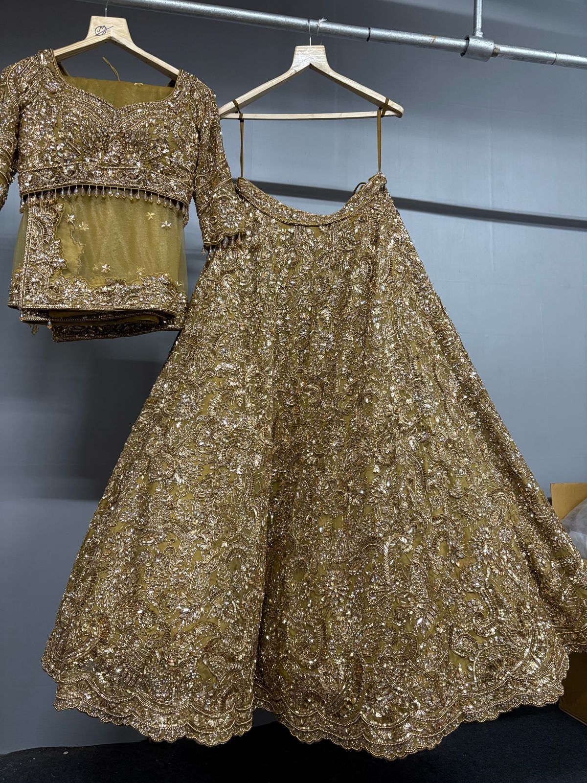 Gold sequined outfit on hangers against a gray wall