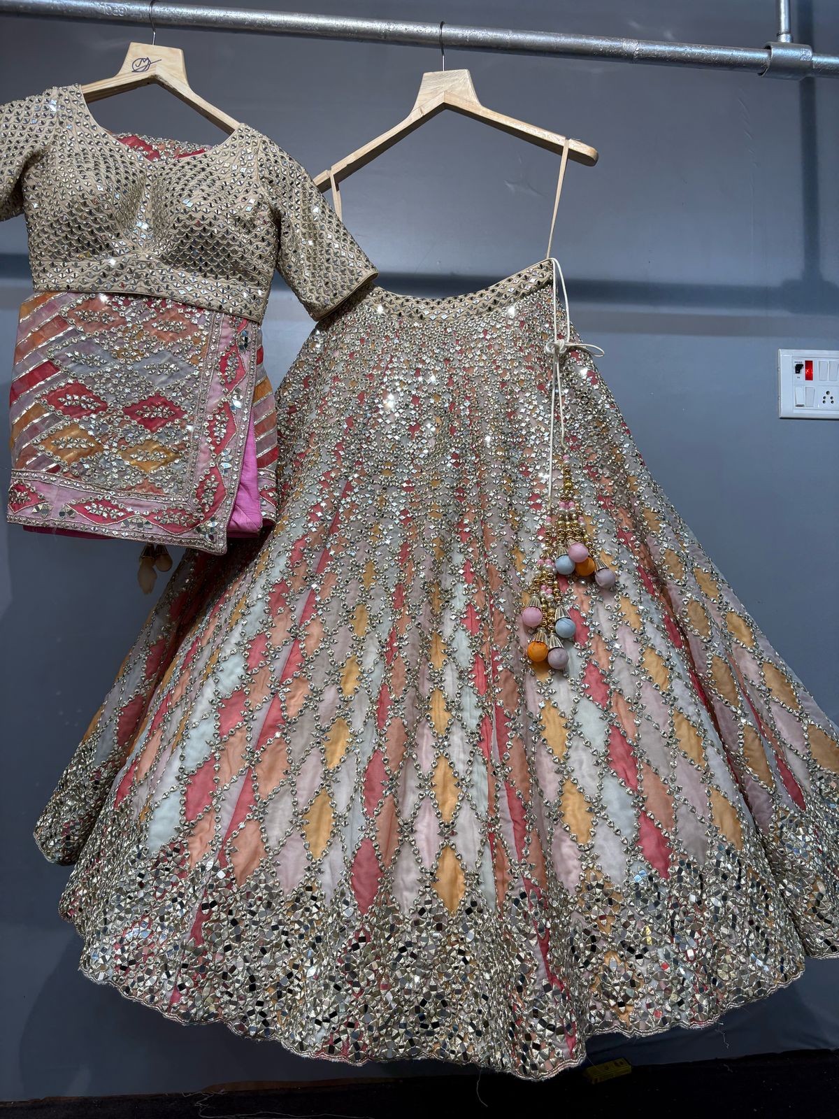 Traditional embroidered outfit with a blouse and skirt on hangers against a dark background