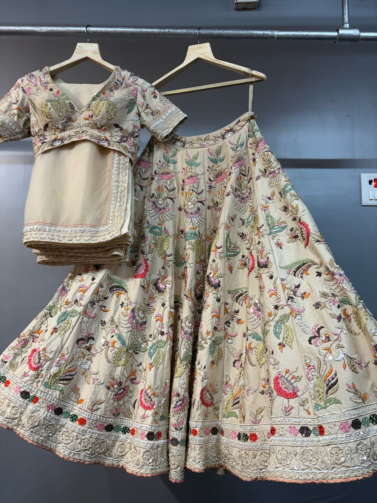 Traditional embroidered outfit on hangers against a dark background