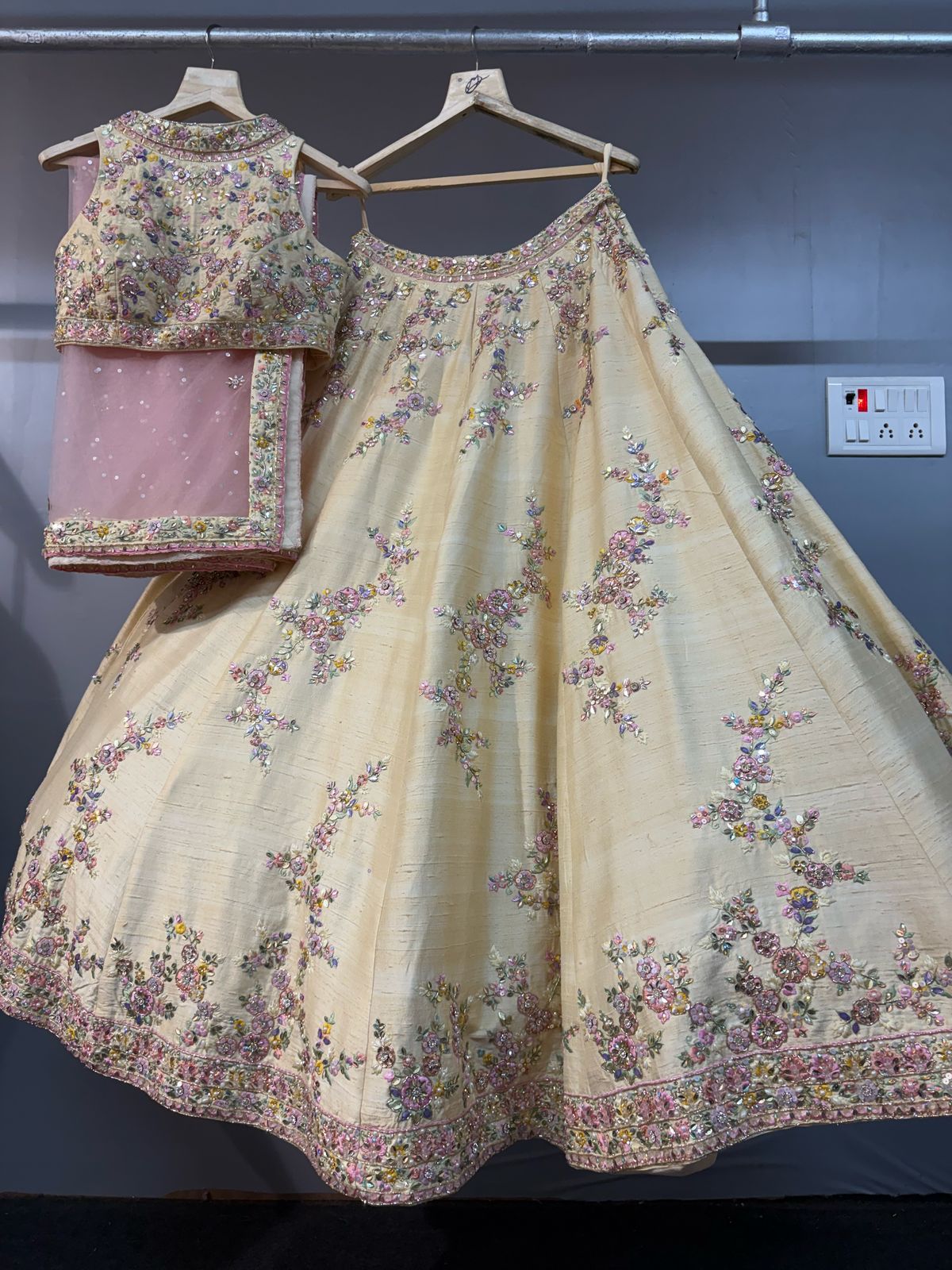 Traditional embroidered outfit on hangers against a plain background