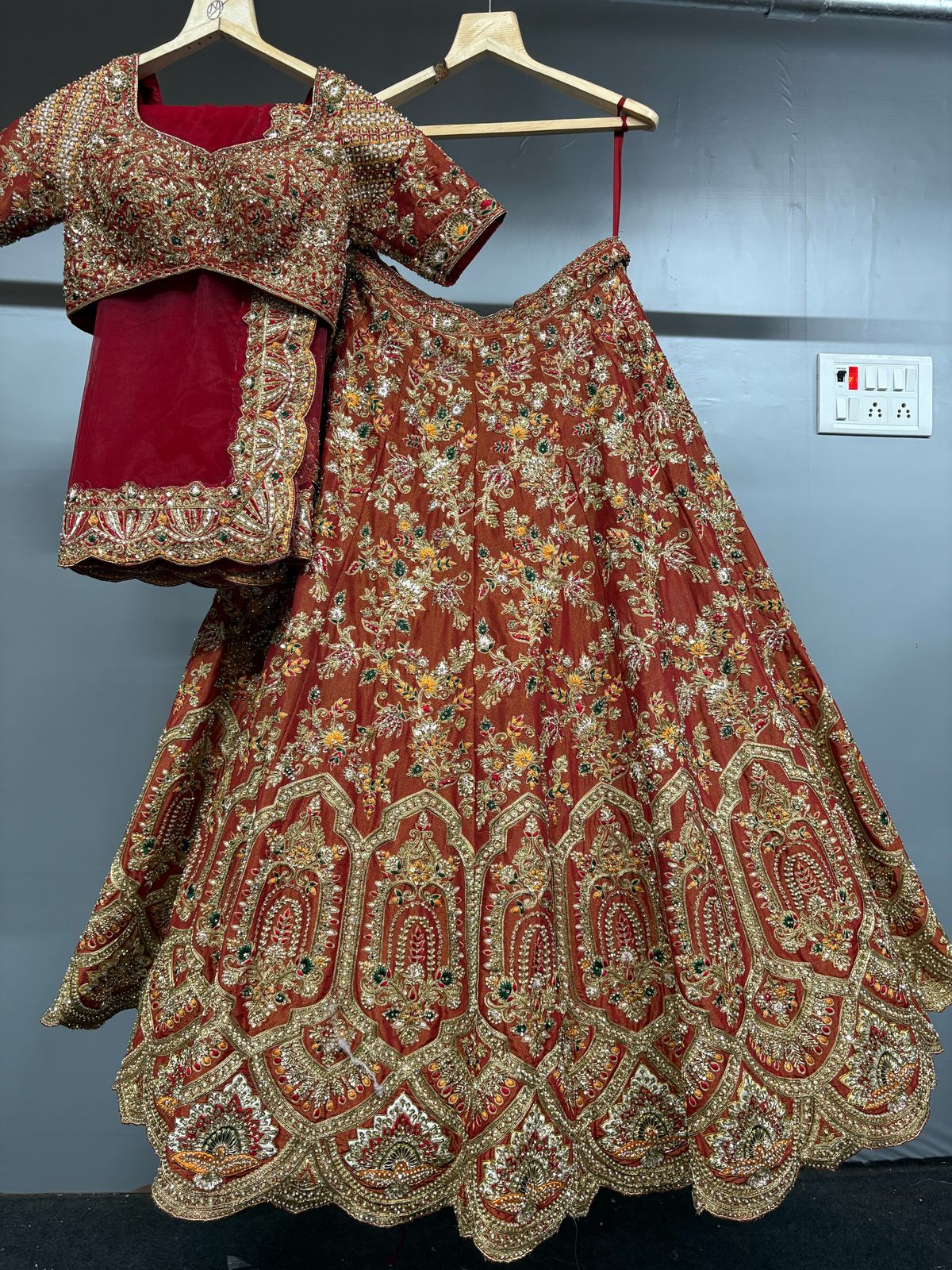 Traditional embroidered outfit with blouse on hangers against a plain background