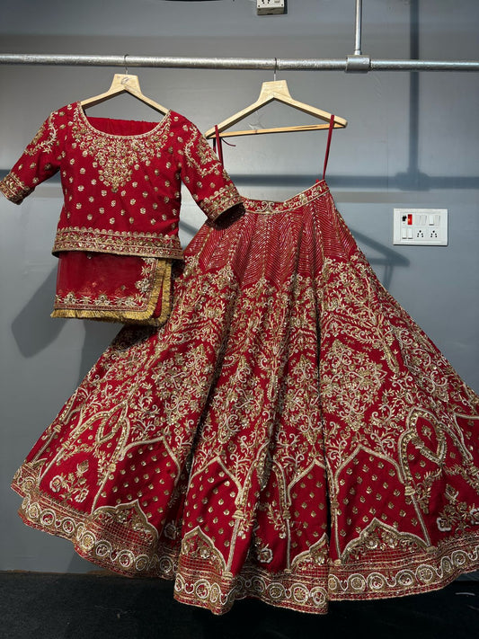 Red embroidered traditional outfit on hangers against a gray wall.