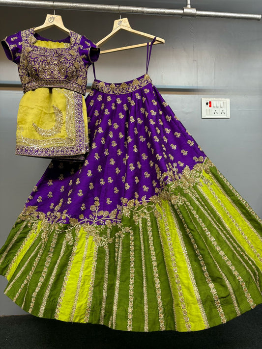 Purple and green embroidered traditional outfit on hangers against a gray wall.