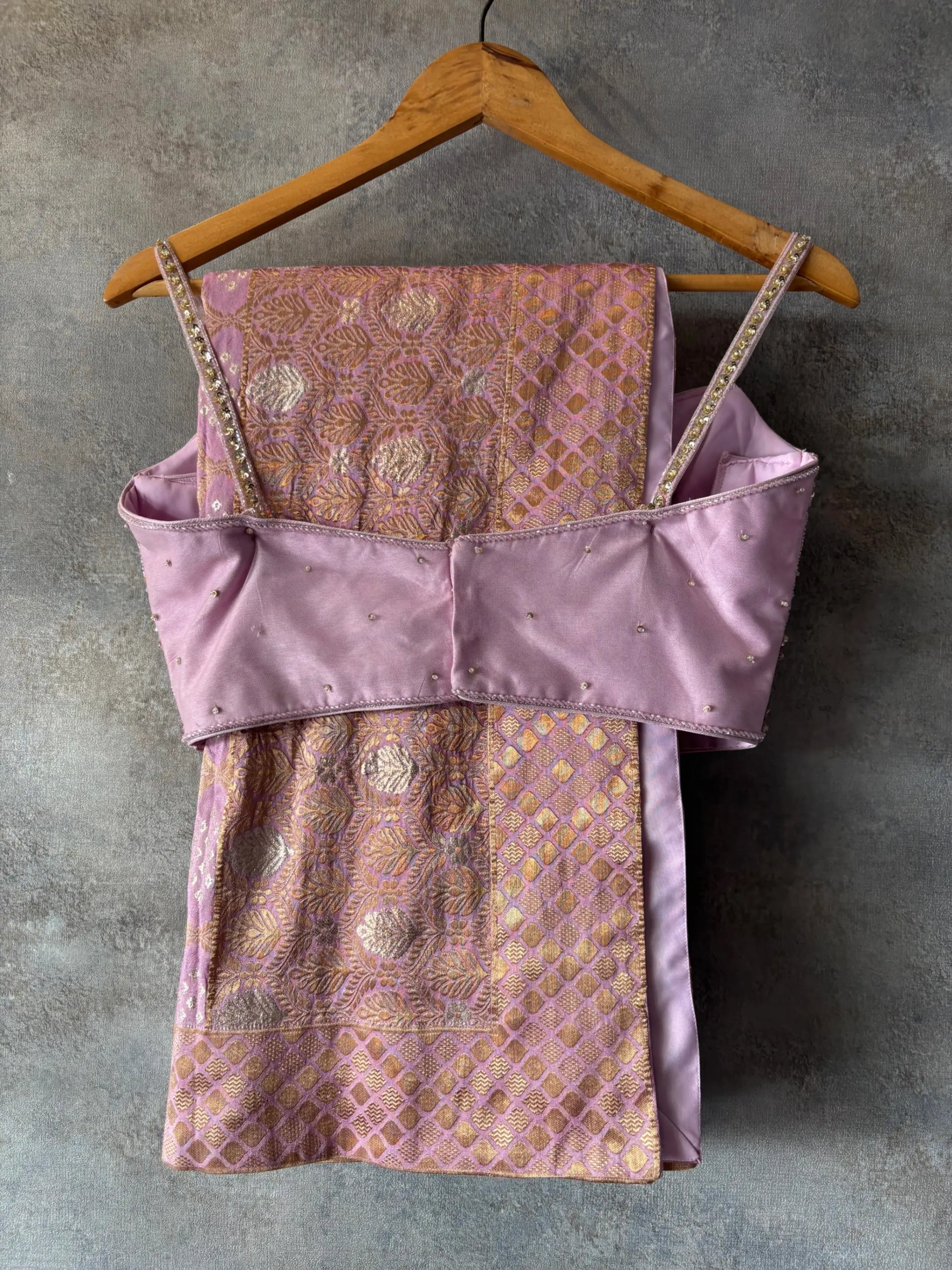 Purple embroidered top and skirt set on a hanger against a gray background