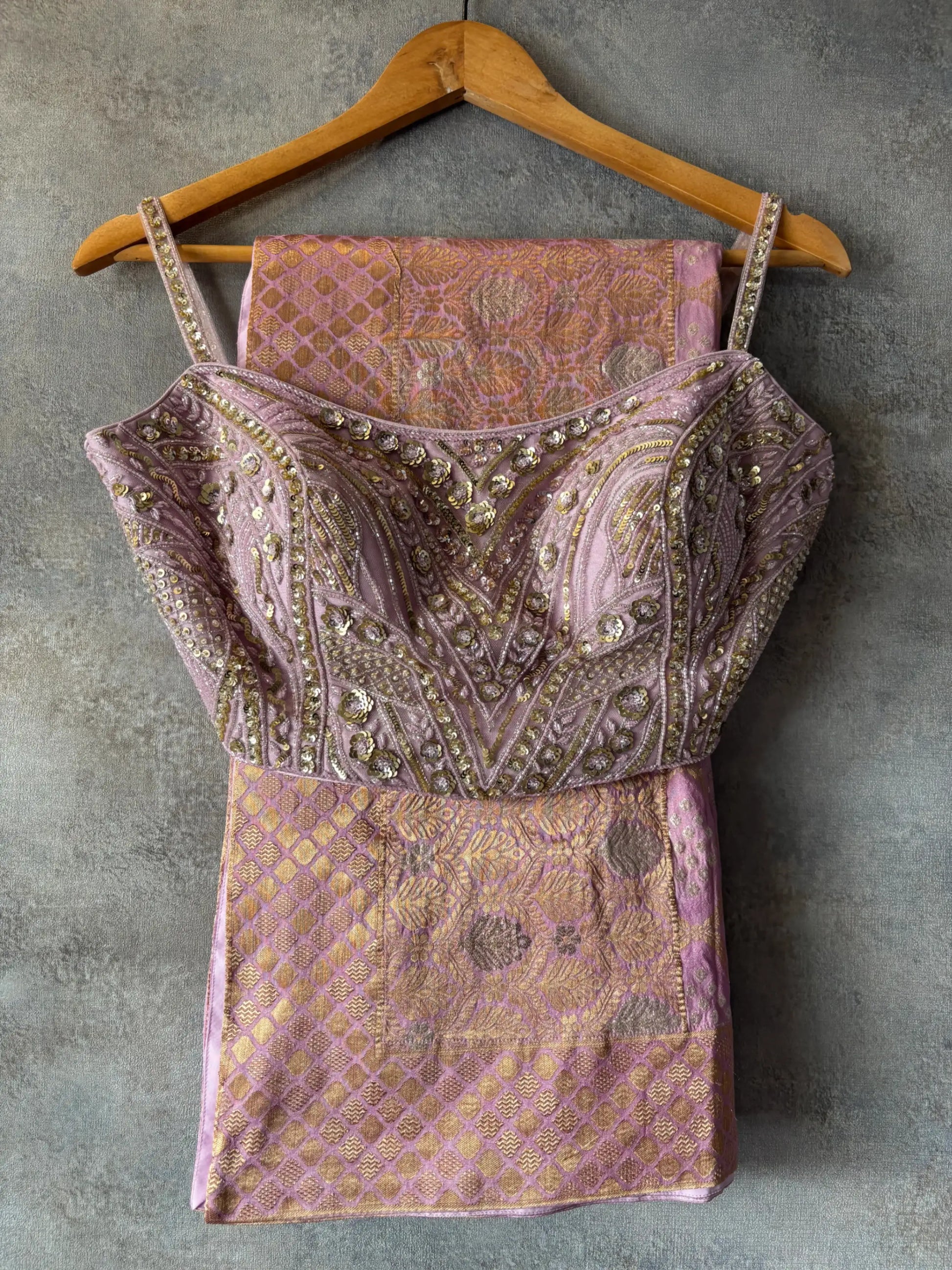 Decorative top with intricate patterns on a hanger against a gray background