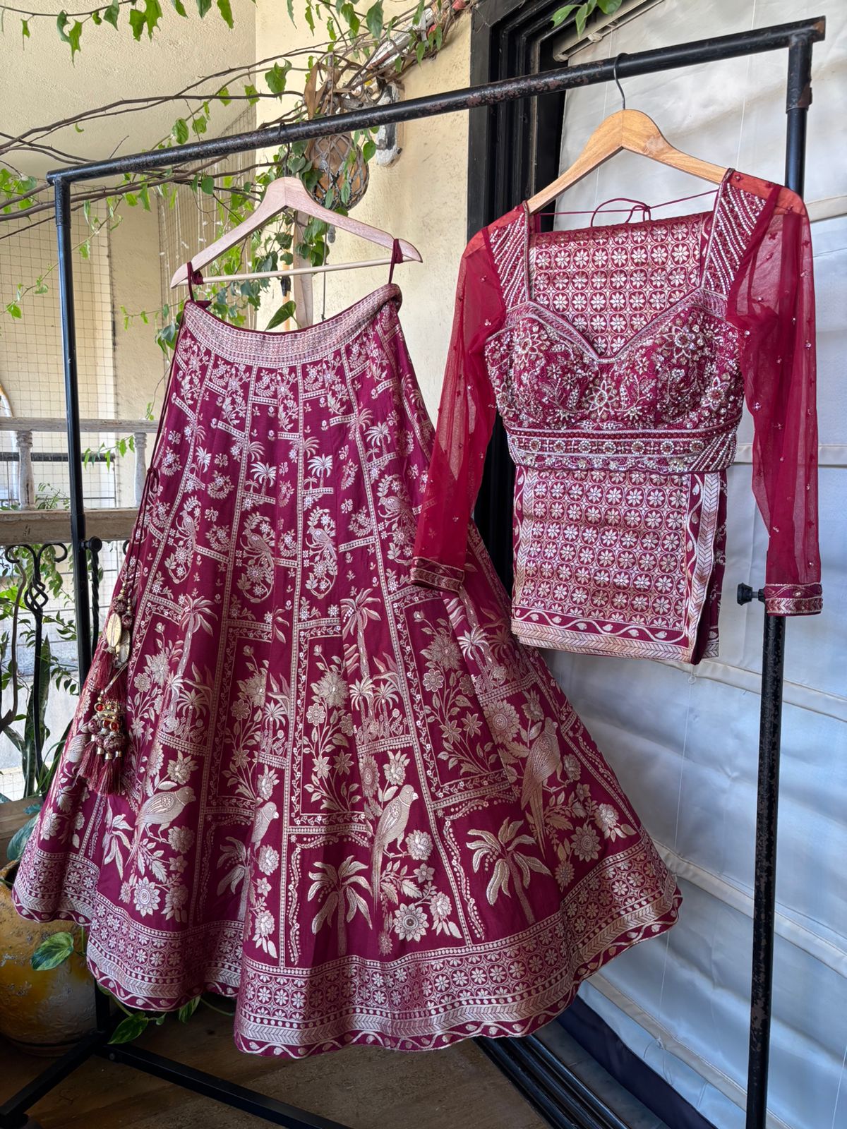 Maroon and white patterned traditional outfit on a rack with a blurred indoor background