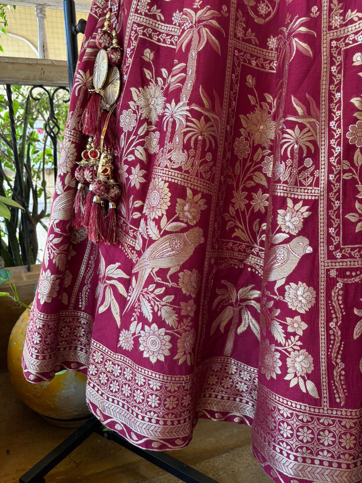 Pink fabric with white floral and bird patterns, hanging on a stand.