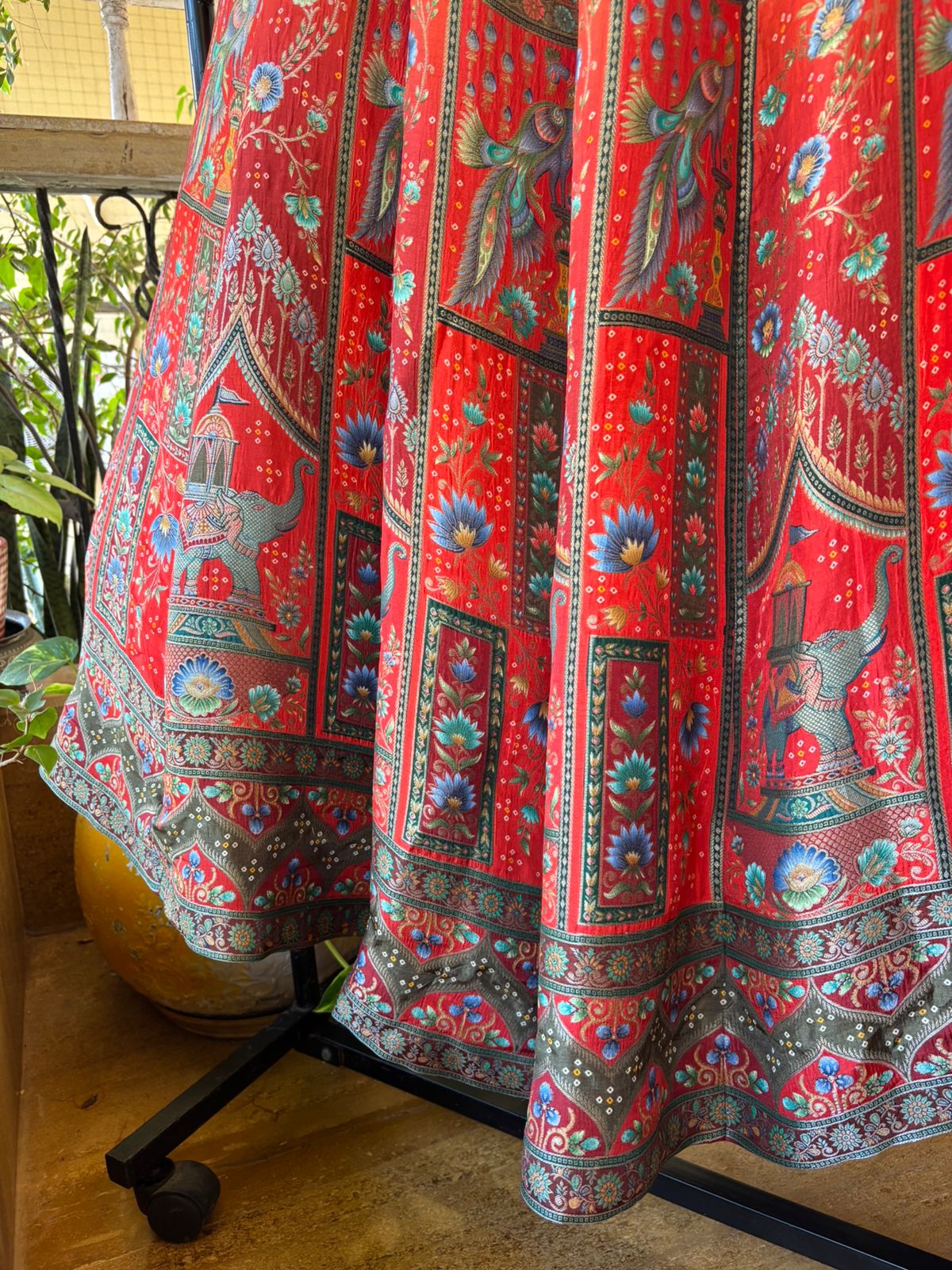 Red patterned skirt on a mannequin against a blurred indoor background