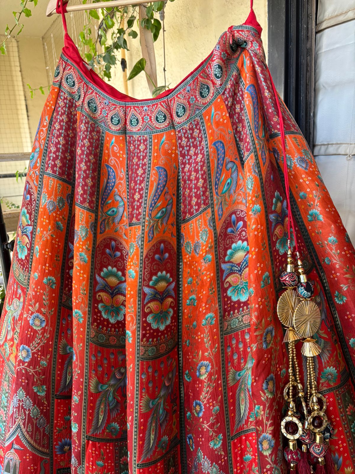 Colorful patterned dress with decorative elements hanging outdoors.